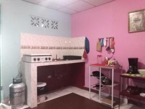 cocina con fogones y pared rosa en Beautiful villa for singles, couples, families and groups cozy stay, en La Chorrera
