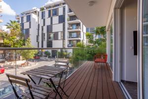 a balcony with a wooden table and chairs and a building at Lapin Premium With Balcony By Nimizz in Tel Aviv