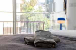 a towel laying on top of a bed with a window at Lapin Premium With Balcony By Nimizz in Tel Aviv
