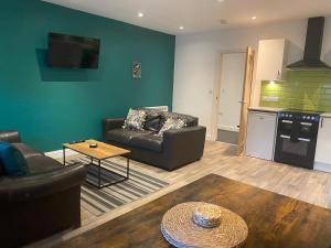 ein Wohnzimmer mit einem Sofa und einem Tisch in der Unterkunft Leckhampton Road Apartments - Cheltenham in Cheltenham