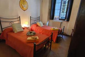 2 camas en una habitación con sábanas de color naranja en La Colonna - La Colonna, en Lucca