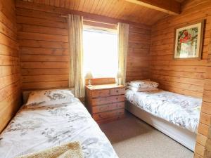 dwa łóżka w drewnianym domku z oknem w obiekcie Strathconon w mieście Acharacle