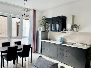 a kitchen with black cabinets and a table with chairs at THE WHITE HOUSE, Modern apartment in Center in Milan
