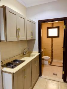 eine Küche mit weißen Schränken, einem Waschbecken und einem WC in der Unterkunft شقق الكوثر الفندقية in Mekka