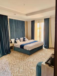 - une chambre avec un grand lit et des rideaux bleus dans l'établissement شقق الكوثر الفندقية, à La Mecque