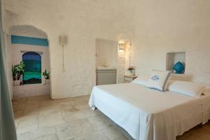 a bedroom with a white bed and a bathroom at Trullisia Bed and Breakfast in Alberobello