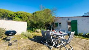 a grill and a table and chairs in a yard at Ensemble de 2 maisons dans les dunes in Le Bois-Plage-en-Ré