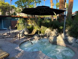 a hot tub with an umbrella in a yard at Vista Grande Resort - A Gay Men's Resort in Palm Springs