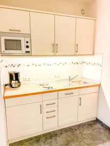 a white kitchen with a sink and a microwave at Waldoase I inkl Sauna-und Schwimmbadnutzung in Bad Harzburg