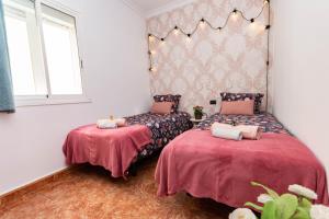 2 Betten in einem Zimmer mit rosa Bettwäsche in der Unterkunft Happy Waves Home in Las Palmas de Gran Canaria