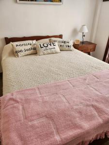 a bed with a pink blanket and pillows on it at Departamento Lo de Martha in Mar del Plata