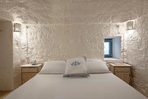 een wit bed met een blauw bloemenkussen erop bij Trullitria Rooms in Alberobello