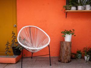 una silla blanca sentada frente a una pared naranja en Lolas Hostal (Hab. privada) baño compartido, en San José