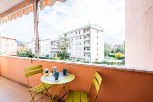 d'un balcon avec une table, des chaises et une fenêtre. dans l'établissement Homiday- Free Parking - Design Flat - Ospedale Cisanello, à Pise