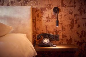 an old fashioned telephone sitting on a table next to a bed at The Yard hotel Noordkade in Veghel +17 photos