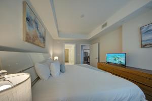 a bedroom with a large white bed and a flat screen tv at Moderno Homes in Fort Lauderdale