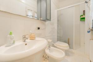 a white bathroom with a sink and a toilet at Villino Aloe - Goelba in Marina di Campo +16 photos