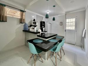 cocina con mesa negra y sillas azules en Bella Peroba Flats #4 Tiffany - Maragogi - AL ' Acessibilidade Kids en Maragogi