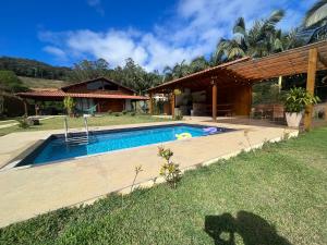einen Hinterhof mit einem Pool und einem Haus in der Unterkunft Chácara cantinho na roça, Domingos Martins - Espirito Santo in Domingos Martins