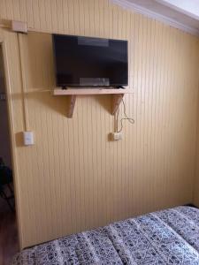 1 dormitorio con TV en la pared y cama en Cabañas y hostal sol de oriente en Puerto Montt