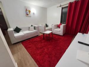 - un salon avec deux canapés blancs et un tapis rouge dans l'établissement Classic all ensuit 3 bedroom in kisumu town, à Kisumu