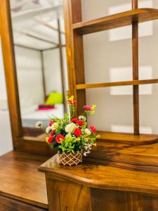 a vase of flowers sitting on a table next to a mirror at Kawshan Home Stay in Hiriketiya