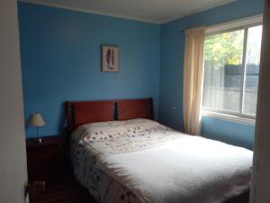 une chambre bleue avec un lit et une fenêtre dans l'établissement Acogedora casa en el sur de Chile, ubicada en barrio residencial, à Puerto Montt