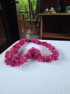 a garland of pink flowers on a white table at Dambulla Tree House in Dambulla