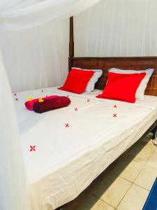 a bed with two red pillows on top of it at Kawshan Home Stay in Hiriketiya