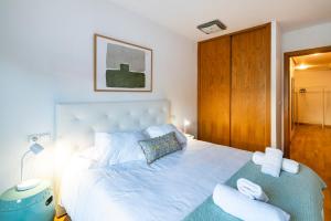 a bedroom with a white bed and a wooden door at El Brezo, apartamento con piscina a 3km de la playa VUT-4389-AS in Llanes