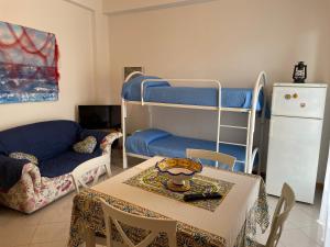 un salon avec une table et un lit superposé dans l'établissement PIETRA BIANCA, à Acireale