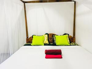 a white bed with green and red pillows on it at Kawshan Home Stay in Hiriketiya