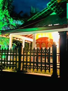 a fence in front of a house at night at Kawshan Home Stay in Hiriketiya