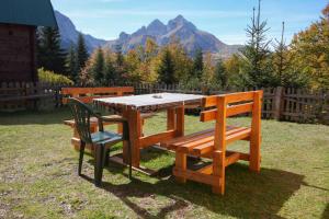 ein Picknicktisch aus Holz und zwei Stühle mit Bergen im Hintergrund in der Unterkunft Weekend House Komovi-Kobildo in Kolašin
