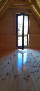 een zolderkamer met een raam en een houten vloer bij Weekend House Komovi-Kobildo in Kolašin