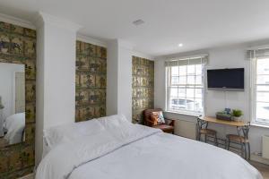 um quarto com uma cama, uma secretária e uma televisão em London Boutique Apartments em Londres