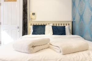 uma cama com cobertores brancos e almofadas em London Boutique Apartments em Londres