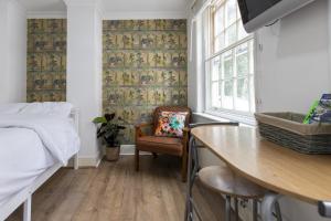a bedroom with a bed and a chair and a table at London Boutique Apartments in London +23 photos