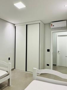 Zimmer mit weißen Wänden und einem großen Spiegel in der Unterkunft Cara da Praia in Guarujá