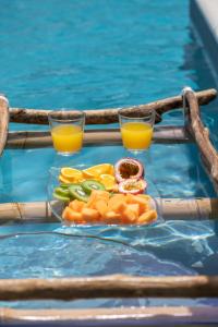 dos vasos de zumo de naranja y verduras en una mesa en una piscina en VILLA HOLIDAYS - Piscine + Vue sur mer + Accès randonnée, en Le Moule