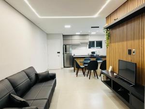 a living room with a couch and a kitchen at Cara da Praia in Guarujá
