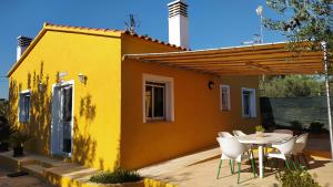 a small yellow house with a table and chairs at Casa Eli in L'Ampolla
