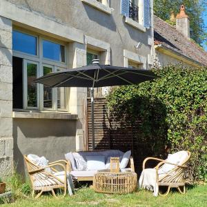 een tafel en stoelen met een parasol in de tuin bij Chambre d'hôtes "Au bord de Loire" in La Marche