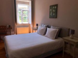 een slaapkamer met een bed met witte lakens en een raam bij Casa de Carrapatelo in Mesão Frio