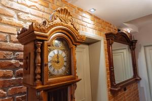 une grande horloge en bois à côté d'un mur de briques dans l'établissement Casta Diva Boutique Hotel, à Korçë