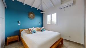 a bedroom with a bed with a blue wall at Les maisons Cane in Sainte-Rose