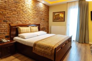 a bedroom with a bed and a brick wall at Casta Diva Boutique Hotel in Korçë