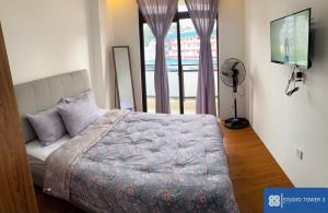 a bedroom with a bed and a flat screen tv at Studio Tower by KR in Baguio