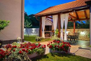 einen Pavillon mit roten Blumen, einem Tisch und Stühlen in der Unterkunft Villa Batarelo in Sinj