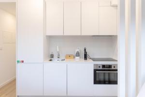 een witte keuken met witte kasten en een wastafel bij FAFEL LITTLE HOUSE - Quinta de Cravaz in Lamego